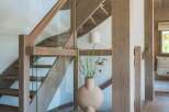 Experience modern living with this stunning staircase featuring natural wood beams and sleek glass railings.