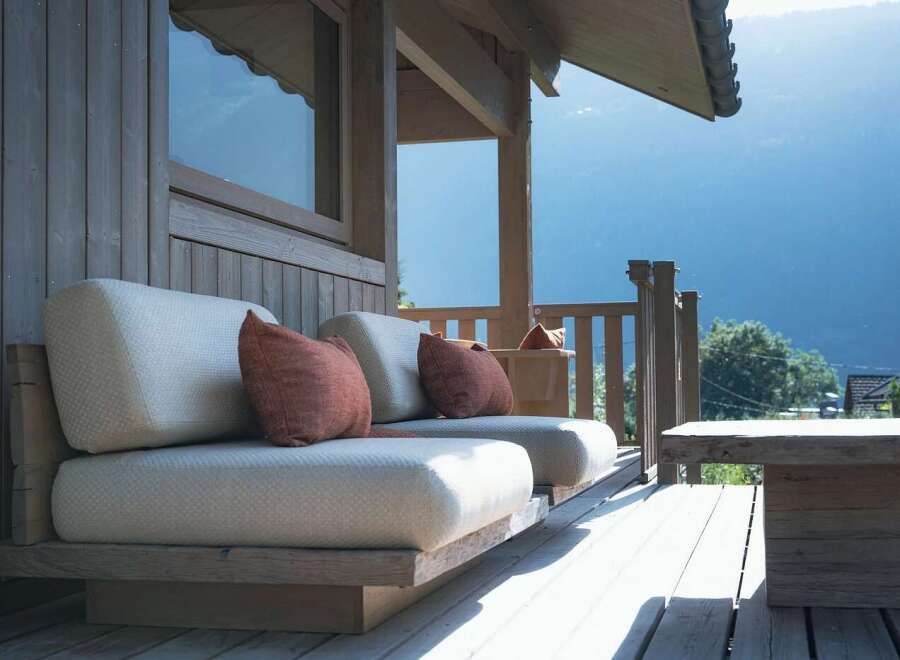 Experience breathtaking mountain views from this stunning wooden deck, featuring comfortable outdoor seating with plush cushions.
