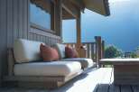 Experience breathtaking mountain views from this stunning wooden deck, featuring comfortable outdoor seating with plush cushions.