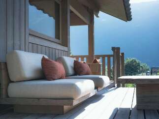 Experience breathtaking mountain views from this stunning wooden deck, featuring comfortable outdoor seating with plush cushions.