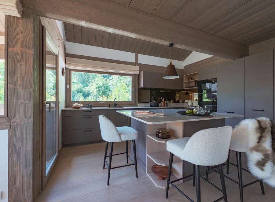 Experience modern mountain living in this stunning kitchen featuring sleek grey cabinetry and a spacious island with a marble countertop.