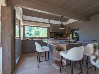 Experience modern mountain living in this stunning kitchen featuring sleek grey cabinetry and a spacious island with a marble countertop.
