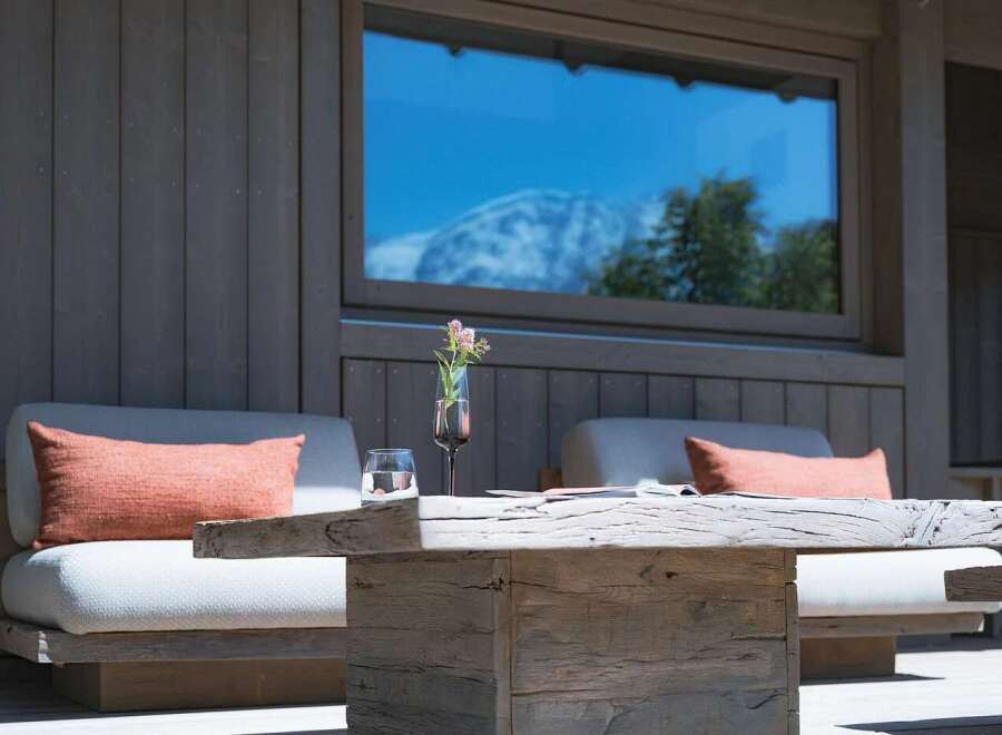 Experience luxurious outdoor living with this inviting seating area, featuring comfortable cushioned chairs adorned with coral throw pillows.