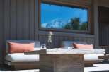 Experience luxurious outdoor living with this inviting seating area, featuring comfortable cushioned chairs adorned with coral throw pillows.