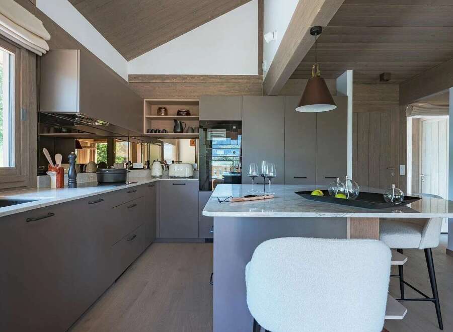 Experience modern living in this stunning kitchen featuring sleek, dark grey cabinetry and a spacious island with a marble countertop.