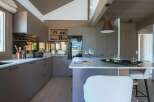 Experience modern living in this stunning kitchen featuring sleek, dark grey cabinetry and a spacious island with a marble countertop.