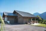 Experience modern mountain living in this stunning wooden chalet, featuring a sleek metal roof and a spacious attached garage.