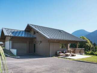 Experience modern mountain living in this stunning wooden chalet, featuring a sleek metal roof and a spacious attached garage.