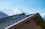 Experience luxury mountain living with this stunning property featuring a modern metal roof and rustic wooden siding, perfectly complementing the majestic snow-capped peaks in the background.