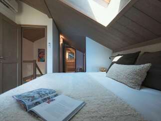 Experience cozy living in this charming attic bedroom, featuring a plush bed adorned with soft linens and decorative pillows.