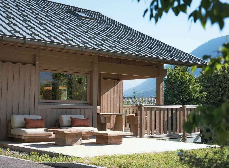 Experience serene mountain living in this charming wooden cabin, featuring a spacious deck with comfortable seating and a rustic wooden table, perfect for enjoying the breathtaking natural surroundings.