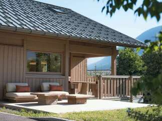 Experience serene mountain living in this charming wooden cabin, featuring a spacious deck with comfortable seating and a rustic wooden table, perfect for enjoying the breathtaking natural surroundings.