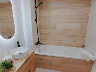 Experience modern comfort in this beautifully designed bathroom, featuring a sleek vessel sink atop a warm wooden vanity.