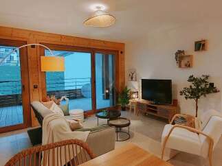 Experience modern living in this beautifully appointed apartment, featuring a spacious living area with a cozy sofa and a large TV.