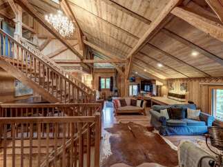 Experience rustic charm in this stunning wooden chalet, featuring a grand staircase and exposed beams that create an inviting, open-concept living space.