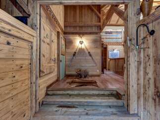 Step into a rustic mountain retreat with this charming entryway, featuring warm wooden walls and a cozy staircase.