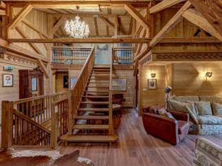 Experience rustic luxury in this stunning wooden chalet, featuring a grand staircase and a sparkling crystal chandelier.