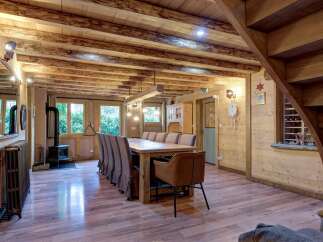 Experience rustic charm in this inviting dining area, featuring a substantial wooden dining table surrounded by upholstered chairs, perfect for family gatherings.
