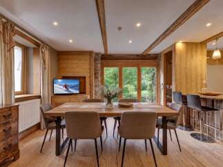 Experience rustic charm in this inviting dining area, featuring a warm wooden table and comfortable upholstered chairs, perfect for family meals.