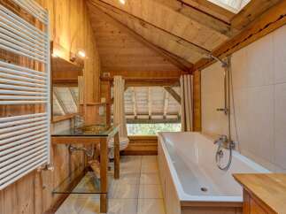Experience rustic charm in this wooden bathroom featuring a deep soaking tub and a unique glass-top vanity with a vessel sink.