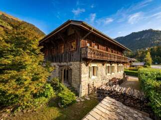 Experience the charm of this traditional alpine chalet, featuring rustic wooden architecture and a stone base, perfect for a cozy mountain getaway.