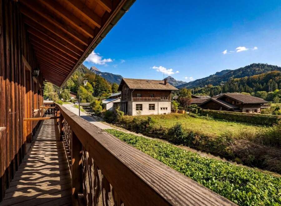 Experience the charm of this alpine retreat, featuring a rustic wooden balcony offering picturesque views of the surrounding mountains and lush greenery.