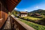 Experience the charm of this alpine retreat, featuring a rustic wooden balcony offering picturesque views of the surrounding mountains and lush greenery.