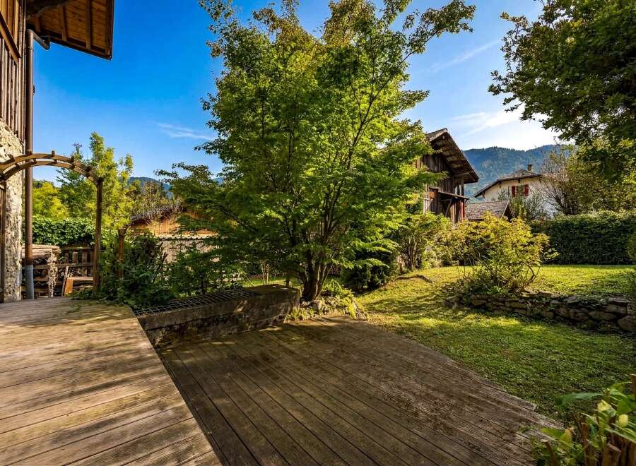 Step onto a charming wooden deck that leads to a lush green garden, perfect for outdoor relaxation.