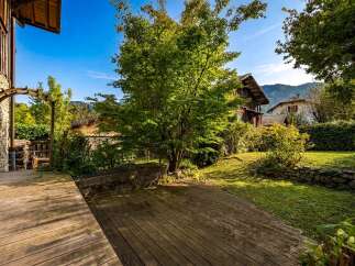 Step onto a charming wooden deck that leads to a lush green garden, perfect for outdoor relaxation.