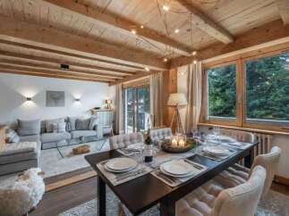 Experience cozy mountain living in this charming dining and living area, featuring exposed wooden beams and a rustic aesthetic.