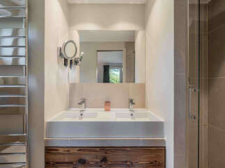 This modern bathroom features a double vanity with sleek chrome faucets and a large mirror.