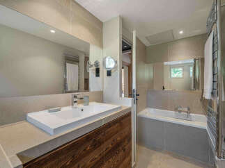 Experience luxury in this modern bathroom featuring a sleek white sink set against a rustic wooden vanity.