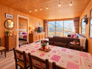 Experience breathtaking mountain views from this charming alpine retreat, featuring a cozy living area with a large window overlooking the stunning landscape.