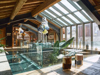 Experience luxury living in this stunning modern chalet, featuring a unique glass floor revealing a lower level with stone accents.
