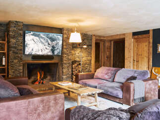 Cozy up by the crackling fireplace in this rustic living room, featuring a large stone hearth and a mounted flat-screen TV.