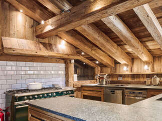 Experience rustic luxury in this stunning chalet kitchen, featuring exposed wooden beams and a charming farmhouse-style range.