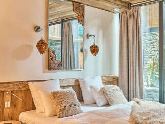 Experience ultimate comfort in this beautifully appointed bedroom, featuring a plush bed adorned with soft white linens and cozy knit pillows.