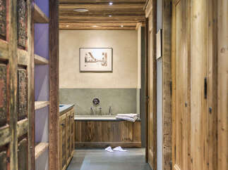 Step into a luxurious bathroom with a rustic charm, featuring a deep soaking tub set against a textured stone wall.