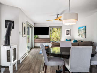 Experience comfortable living in this inviting dining and living area, featuring a modern white wood-burning stove and a sleek black dining table with upholstered chairs.