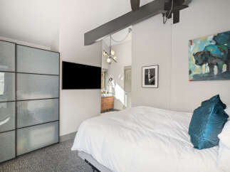 Experience modern comfort in this stylish bedroom, featuring a plush king-sized bed adorned with elegant teal accent pillows.