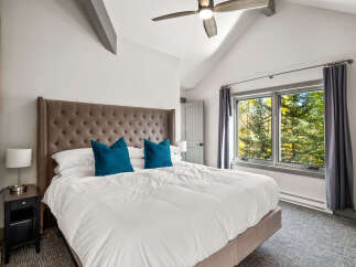 Experience ultimate comfort in this inviting bedroom, featuring a plush king-sized bed with a striking tufted headboard and two vibrant teal accent pillows.