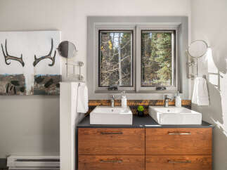 This modern bathroom features a double vanity with two vessel sinks and sleek chrome faucets, set against a backdrop of rustic wood paneling.