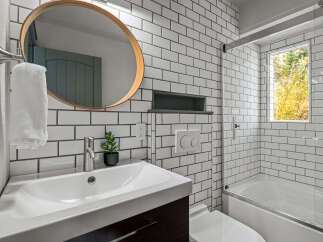 This modern bathroom features crisp white subway tile walls and a sleek vanity with a vessel sink.