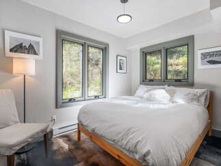 Experience serene comfort in this charming bedroom, featuring a plush queen-size bed dressed in crisp white linens.