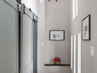 Step into a hallway featuring a stylish barn door and a striking starburst chandelier that illuminates the space.