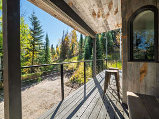 Experience the beauty of autumn from this charming covered porch, offering stunning views of colorful foliage and evergreen trees.