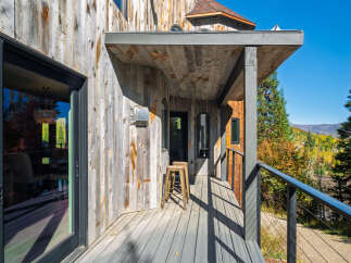 Experience the rustic charm of this mountain retreat, featuring a weathered wood exterior and a covered porch perfect for enjoying the crisp autumn air.