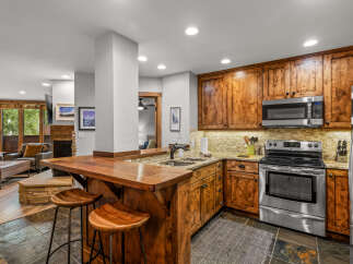 Experience rustic charm in this mountain-style kitchen featuring warm, knotty pine cabinetry and a stunning live-edge wood bar perfect for entertaining.