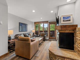 Cozy up by the stone fireplace in this inviting living room, featuring plush leather seating and a rustic wooden coffee table.