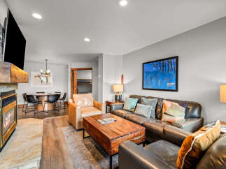 Cozy up by the stone fireplace in this inviting living room, featuring a large leather sectional and a rustic wooden coffee table.